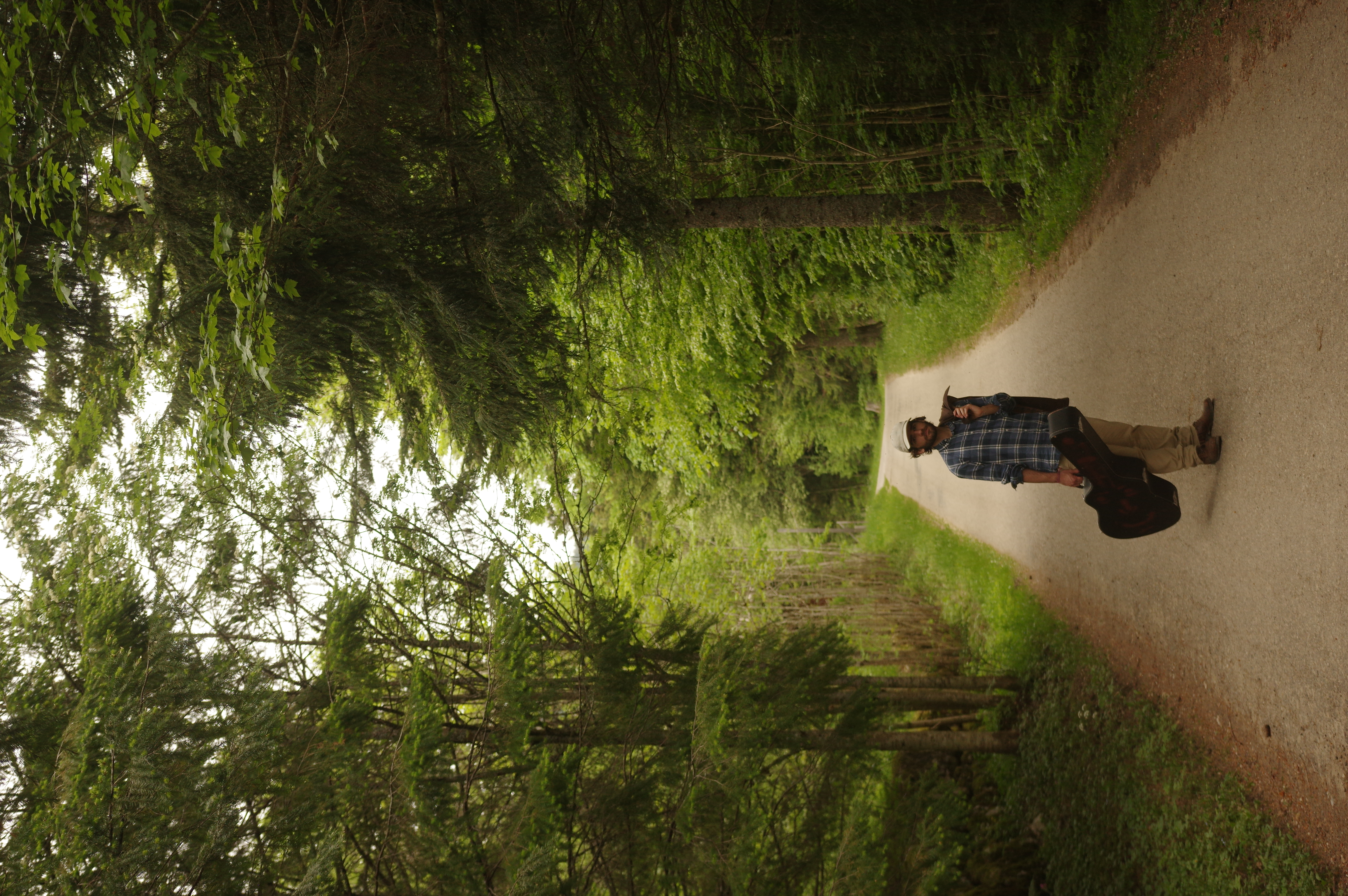 C4C standing on a forest road with a guitar case, reflecting the nature-rooted and acoustic world of Folk-Hop